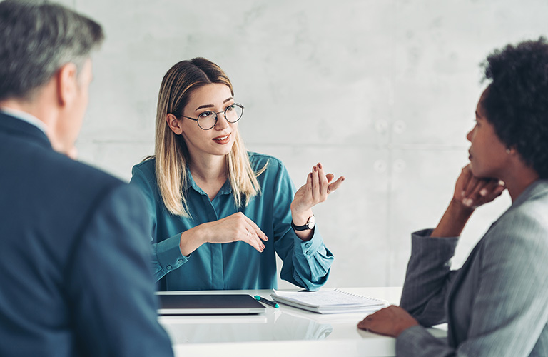 A professional speaking to two people across a table.
