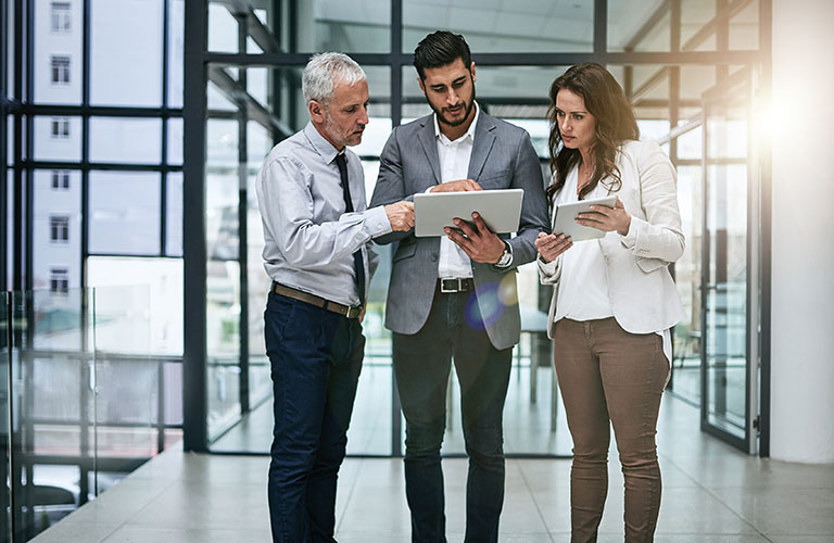 Three managers review business documents on their tablets