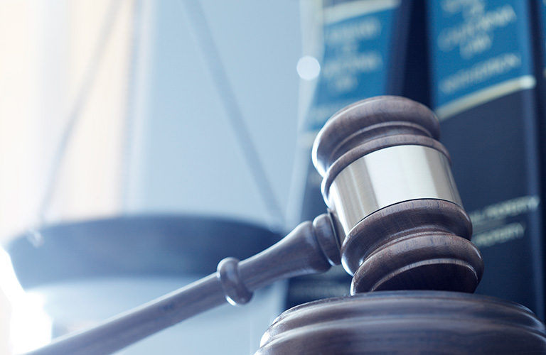 Photo of a gavel with scales of justice in the background.