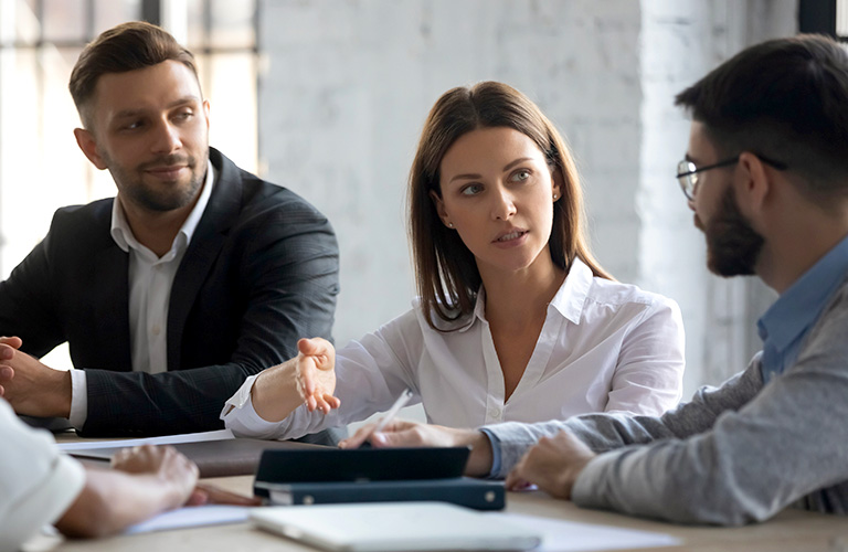 Professionals listening to someone speak in a team meeting.