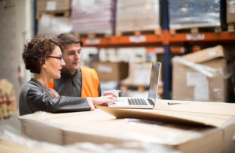 Two people in a warehouse working around a laptop.