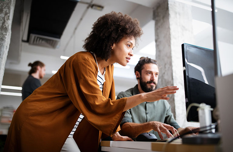 Two professionals consulting at a computer.