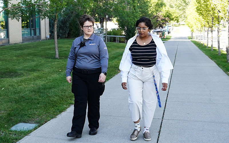A Security Services team member walking with an employee on the grounds.