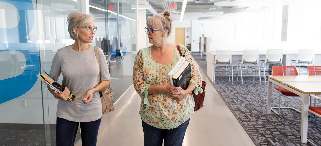 Two professionas chatting and walking in the Riddell Library and Learning Centre.