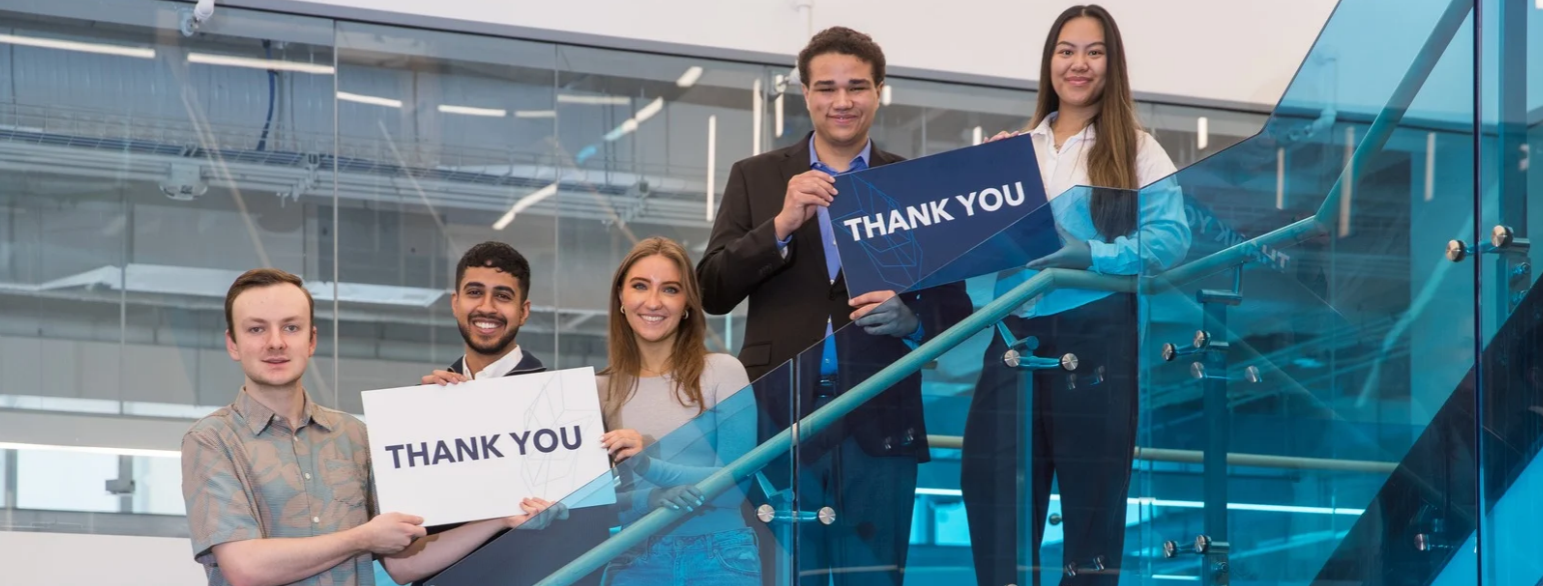 Students on a staircase holding signs that say thank you