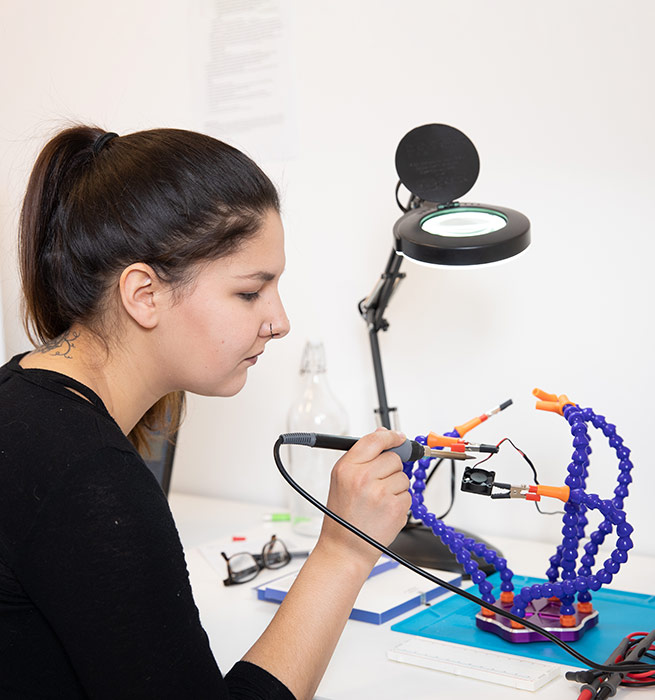 A young Indigenous woman working on a robotics kit in Mount Royal University's Maker Studio.