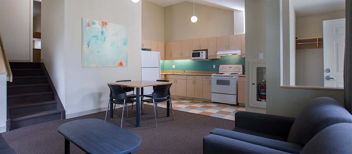Interior of a residence suite on campus - it shows the living room and kitchen.