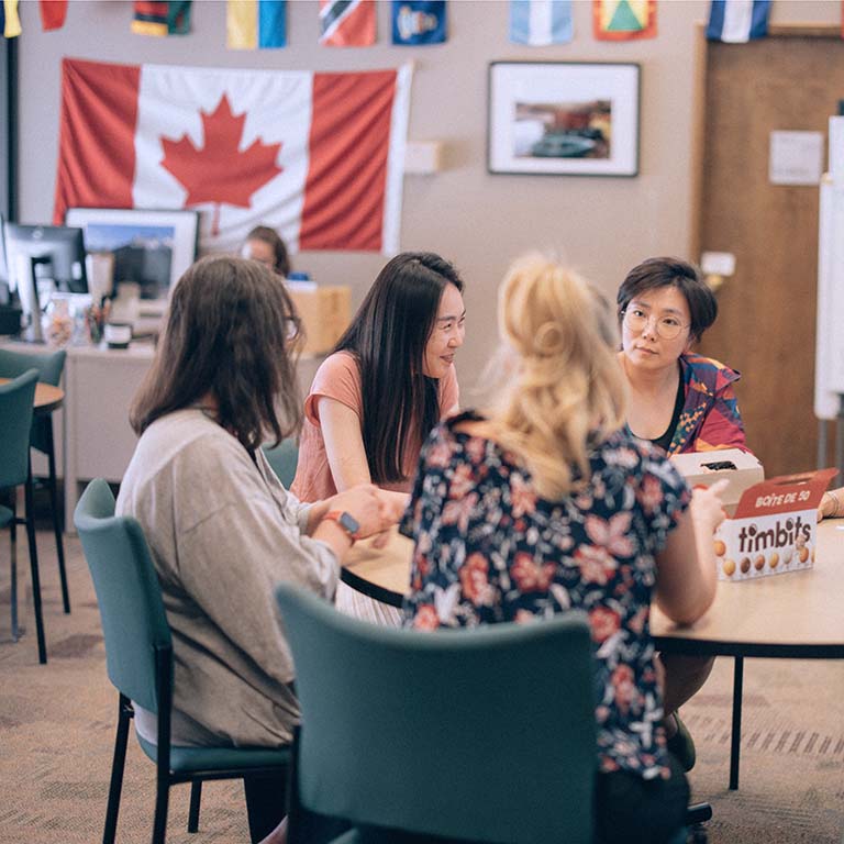 A group of students and staff enjoying conversation and Timbits in the Global Student Lounge.