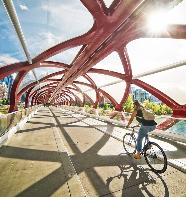 Calgary's Peace bridge — intersecting red beams creating a tunnel over a cyclist and pedestrian bridge.