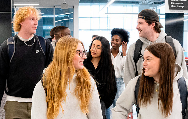 A group of students chatting as they walk through the Riddell Library and Learning Centre.