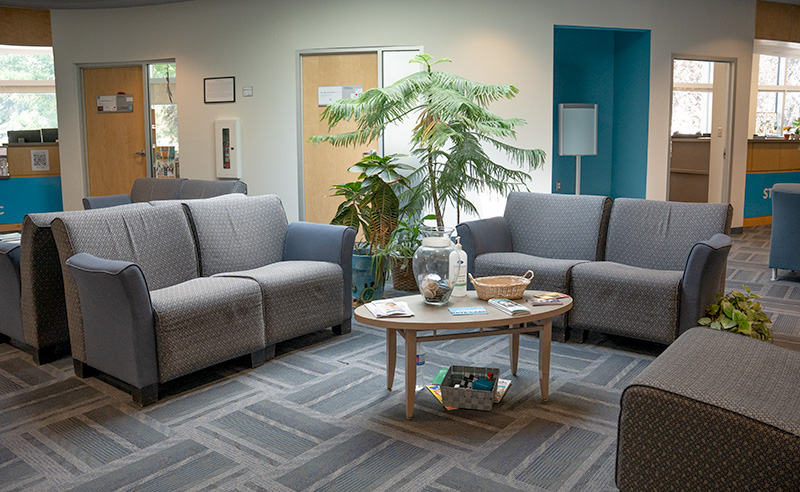 The waiting area of Wellness Services featuring plans, couches and offices in the background.