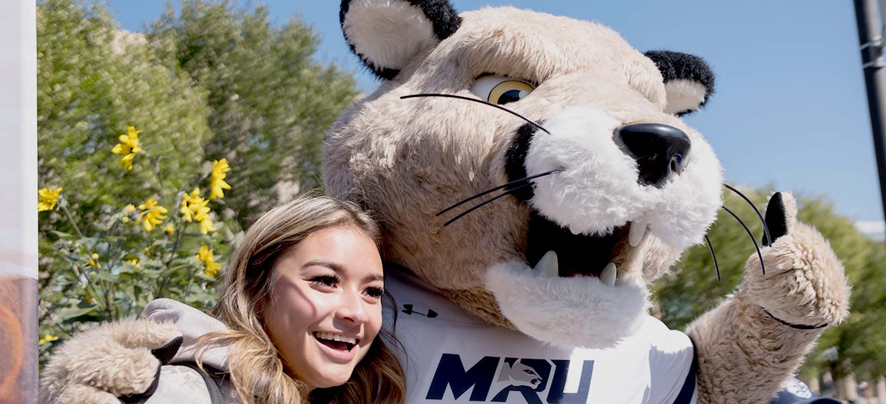 A student taking a selfie with MRU Cougars' mascot, Calvin.