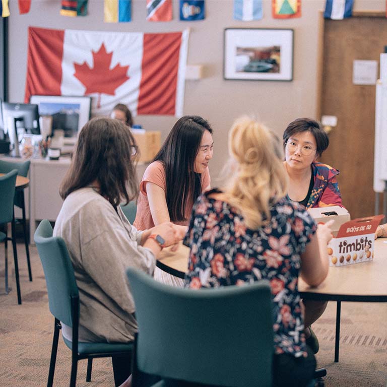 A group of students and staff enjoying conversation and Timbits in the International Student Support Centre.