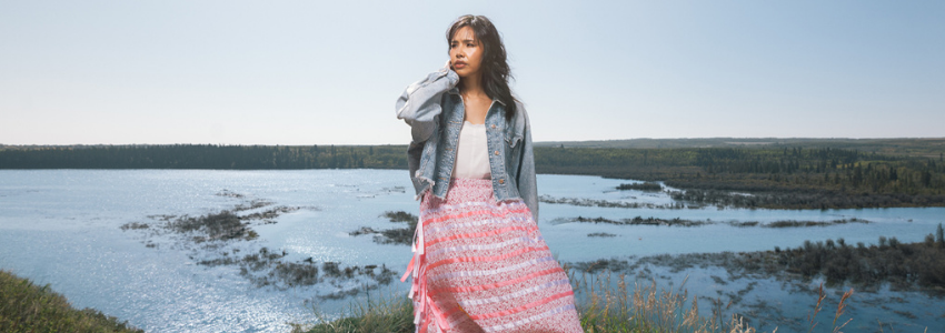 Sofia Baptiste stands on a path near a lake, framed by nature.