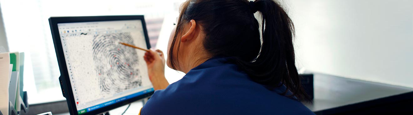 A woman inspecting a scan of a fingerprint on a computer