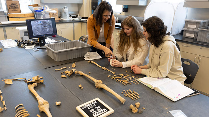 Dr. Rebecca Gilmour, PhD works with alumni assistant Jessica King and and current student assistant Cerena Bond analyzing the remains of an ancient Roman skeleton