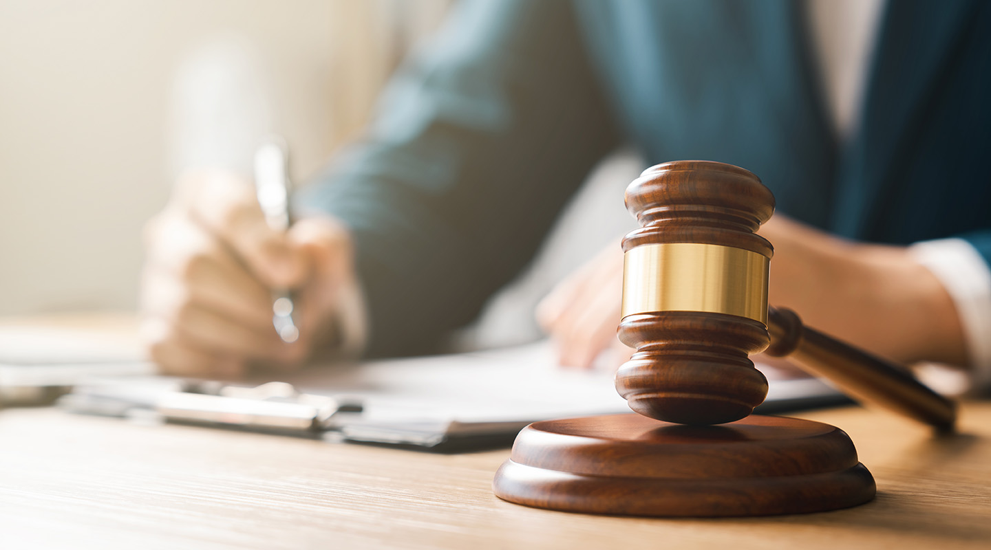 A person reviewing documents at a desk with a gavel resting on a wooden sound block.