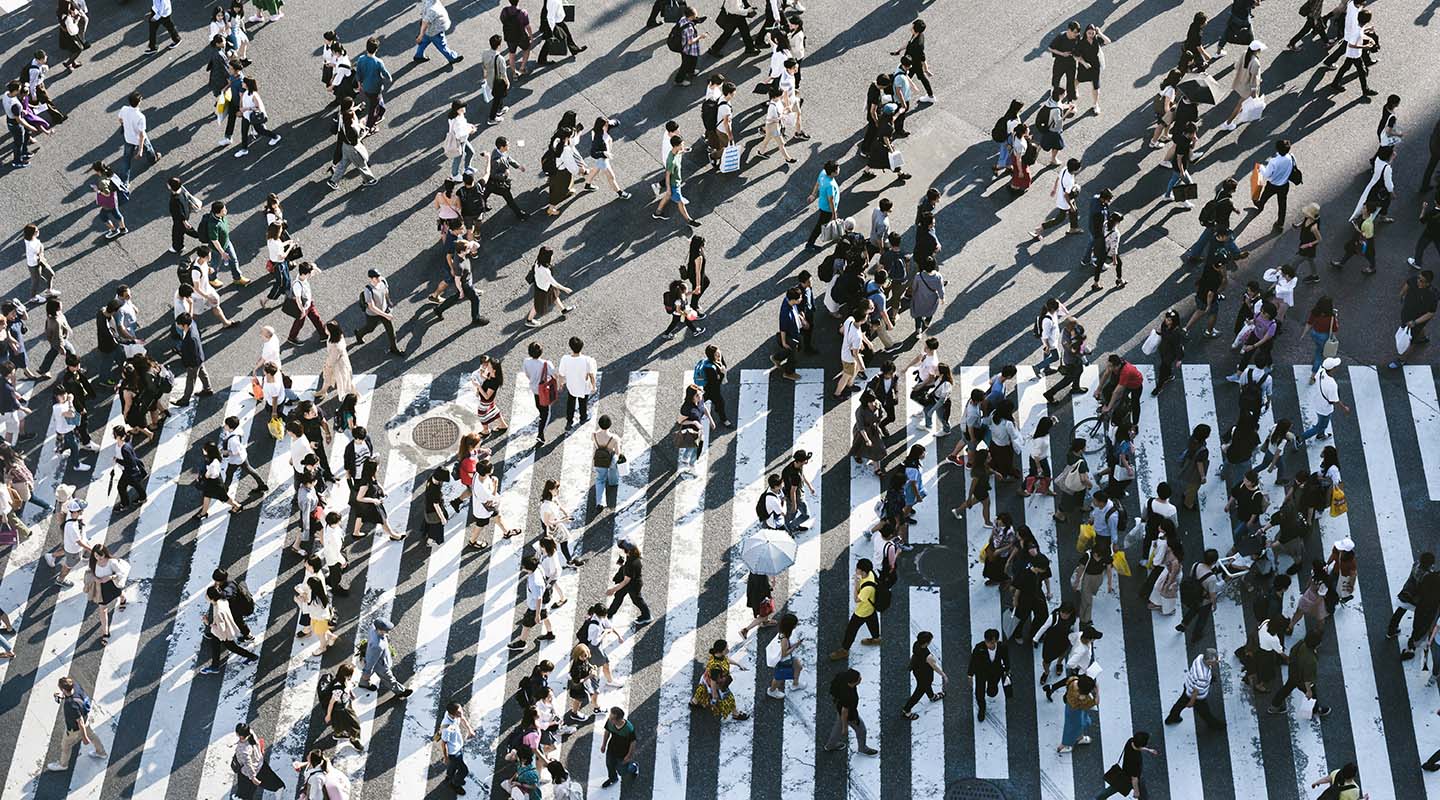 A busy zebra crossing filled with many pedestrians walking in different directions.