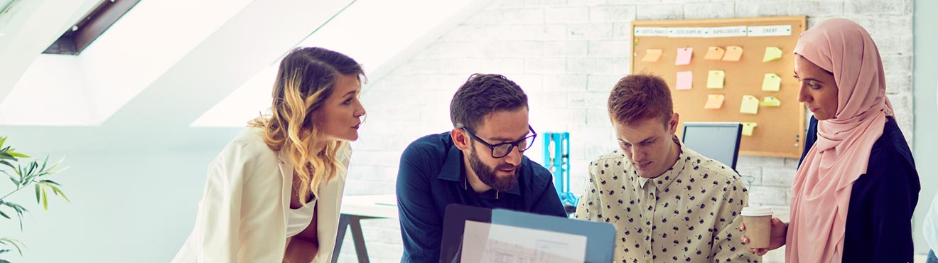 A group of young business professionals reviewing something in an office.