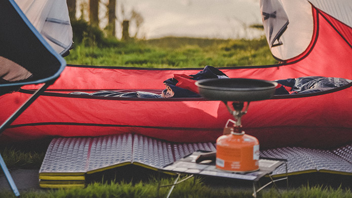 Camping set up with a tent, chair and small propane stove.