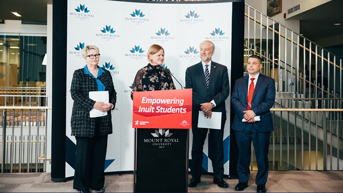 Dr. Kelly Williams-Whitt (dean of the Faculty of Business and Communications Studies), Deanna Weibe (academic director and chief flight instructor of MRU Aviation), Michael Rodyniuk (Canadian North CEO and Mount Royal alumnus) and Jason Kilabuk (Canadian North’s director of Inuit employment) stand together at a podium.