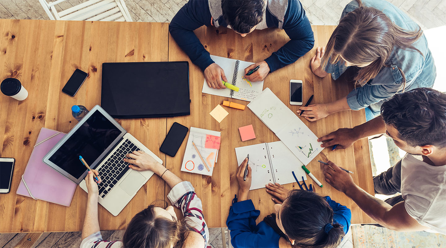 A top-down photo of a group of students working together on a project.