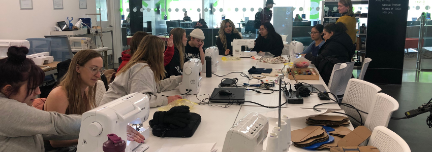 BCST students sitting in Maker and Media commons making sootsiman an Indigenous decorated rawhide bag