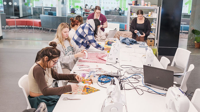 Bachelor of Child Studies student sit around table in the Makers space while creating their own Sootsiman