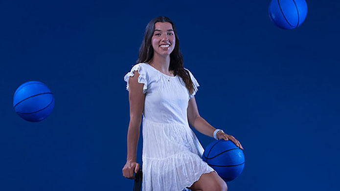 Photo of Marnie Garner on a stool with basket balls falling around her.