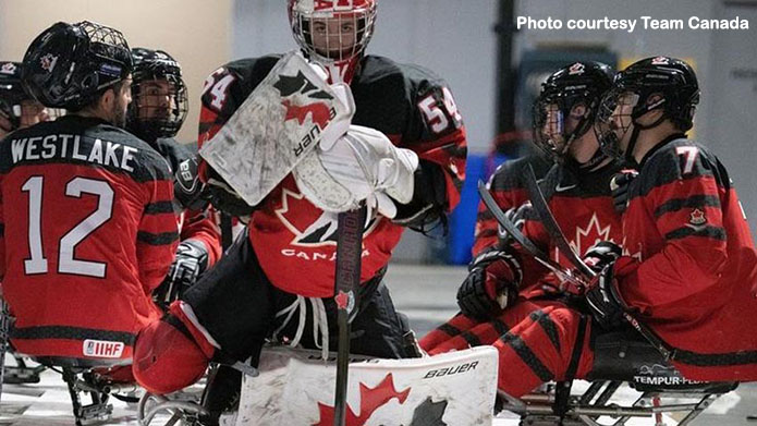 Adam Kingsmill on the ice surrounded by teammates.