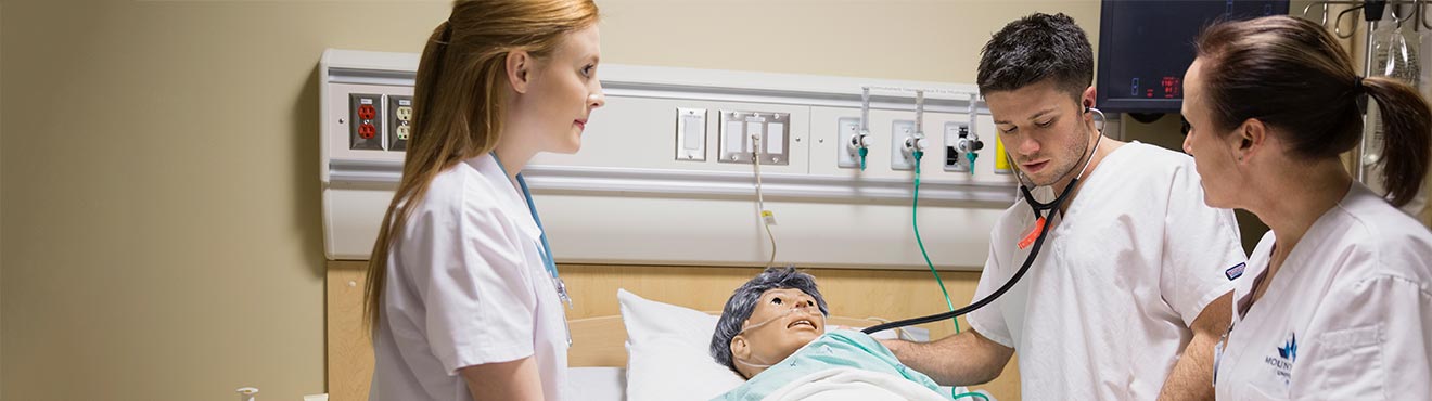 a group of students monitoring a dummy in the Simulation Learning Centre.