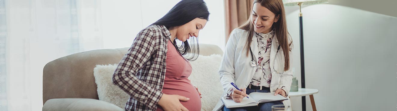 A midwife and a pregnant person on a couch during a consult.