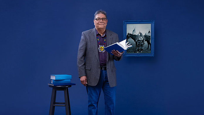 Photo of Roy Bear Chief in front of a blue backdrop.
