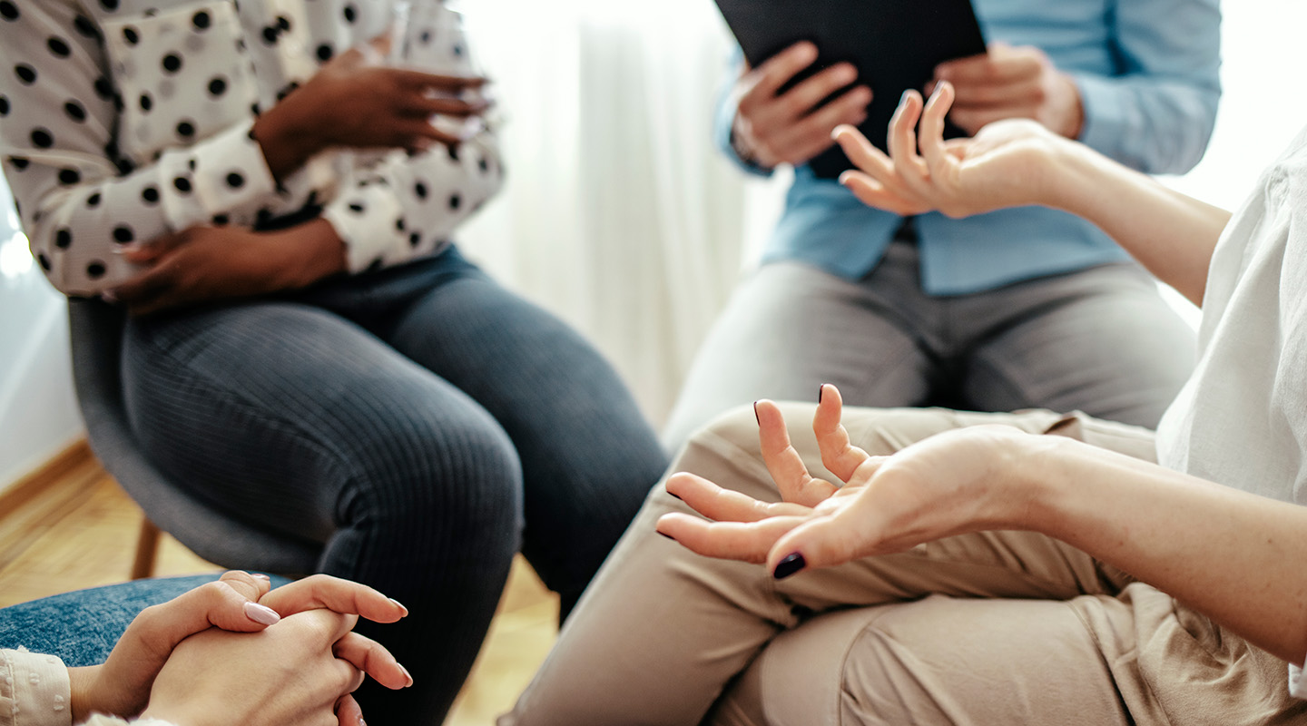 A group of people sit in a circle during group therapy.