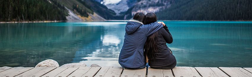 Two people sitting on a dock at Lake Louise, Alberta.