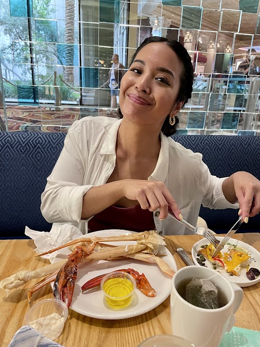 Melissa smiles proudly as she cuts into her seafood meal.