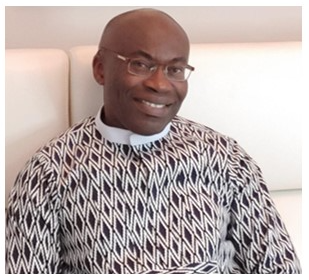 Dr. Michael Uzoka wearing glasses and patterned sweater