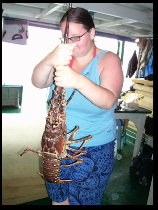 Amy Stromquist wearing glasses and tank top with shorts and holding a large lobster