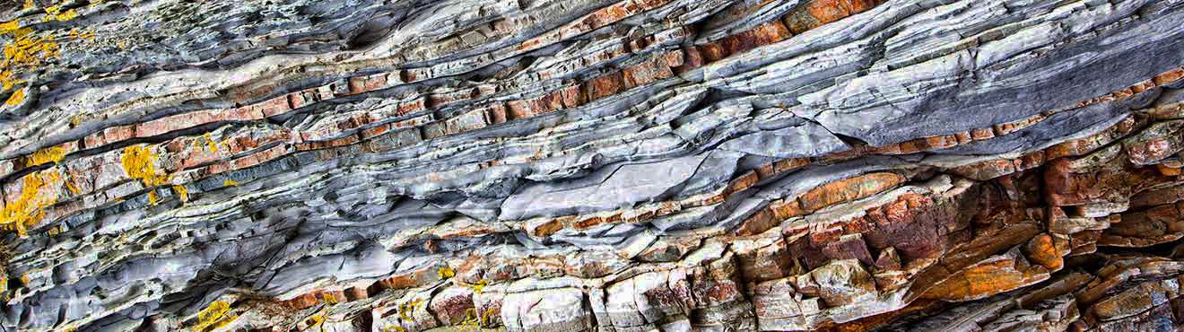 Photo of a rock wall that has many different colours and layers.