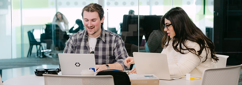 Two students working on laptops in the Maker Studio at the Riddell Library and Learning Centre.