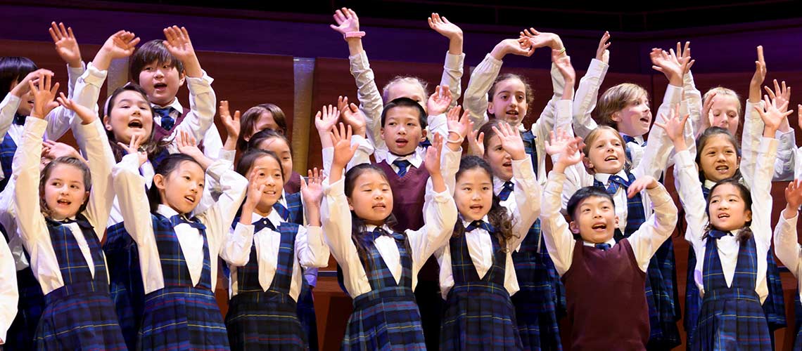 A group of children on a stage or hands in the air.