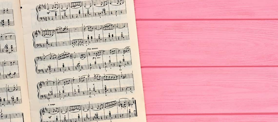 Photo of sheet music on a bright pink wood table.