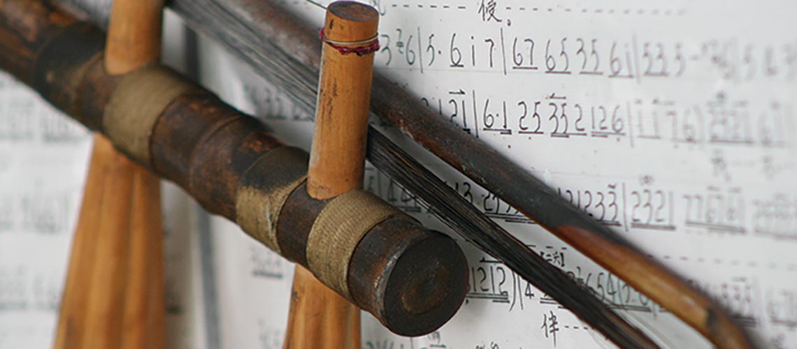 Close up of an Erhu over a sheet of musical notation