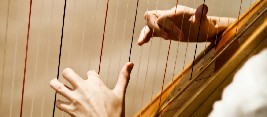 Close up photo of hands playing a harp.