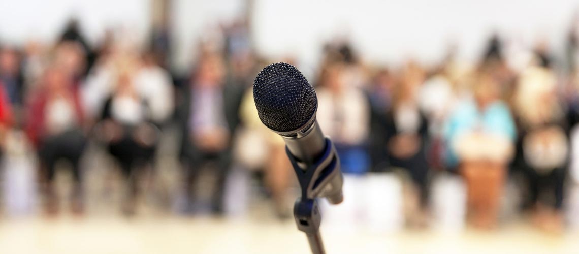 Close up of a microphone in front of a crowd.