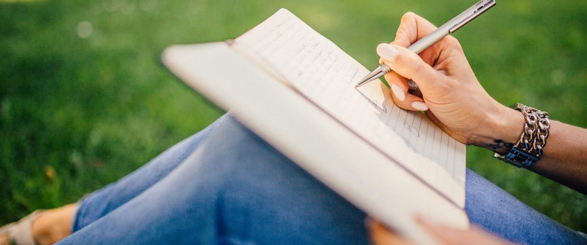 Person writing in a book outside