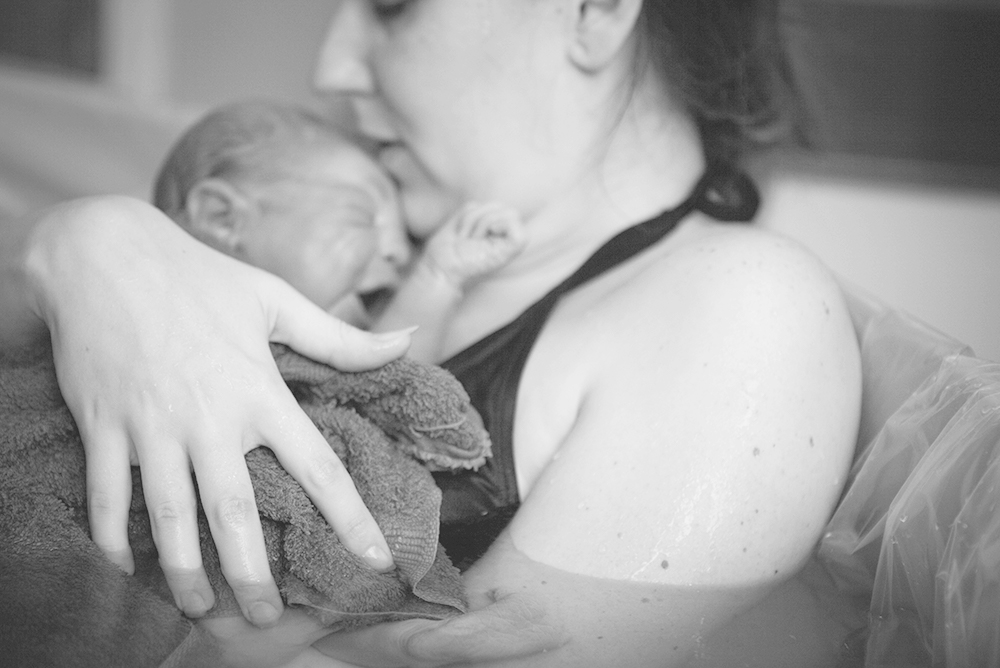 A new mother clutches her newborn child after a water birth.