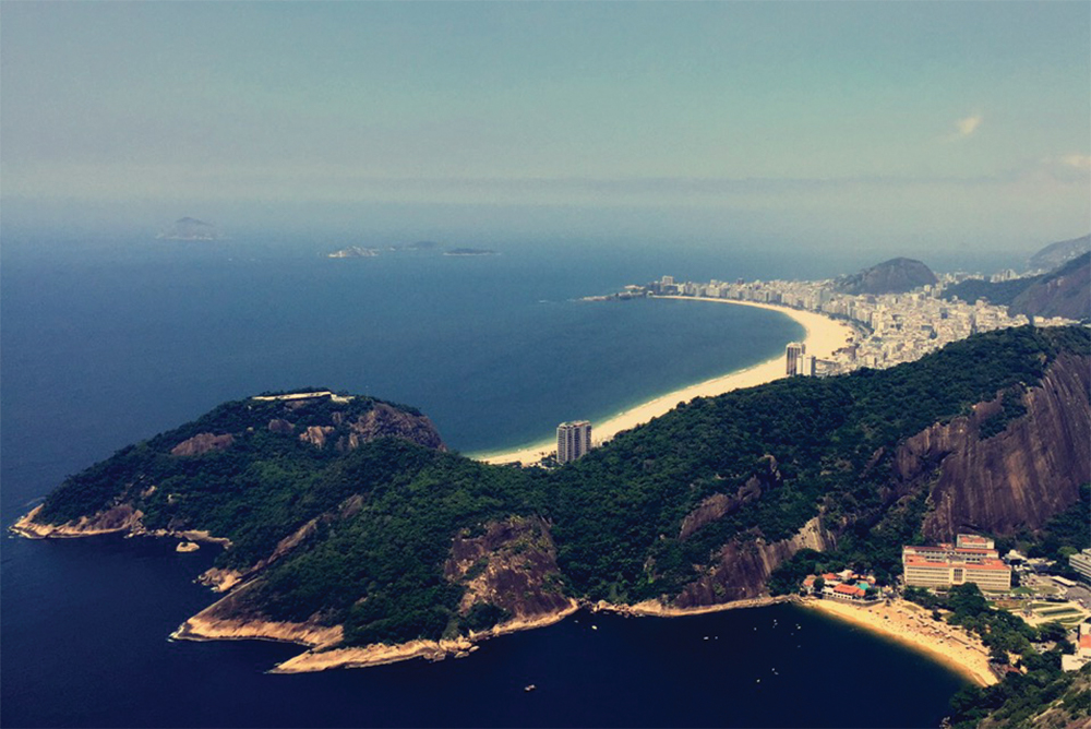 View of Rio de Janeiro from Sugarloaf Mountain, Brazil. It shows a busy metropolis frames by forested mountains and gorgeous beaches.