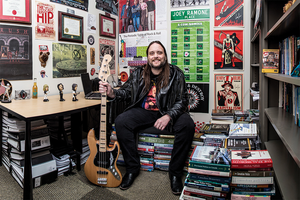 Ben Atkinson props up a guitar in an office covered in band posters and wrestling memorabilia.