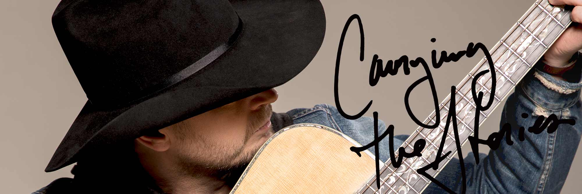 Paul Brandt holds a guitar close and strums the strings gently